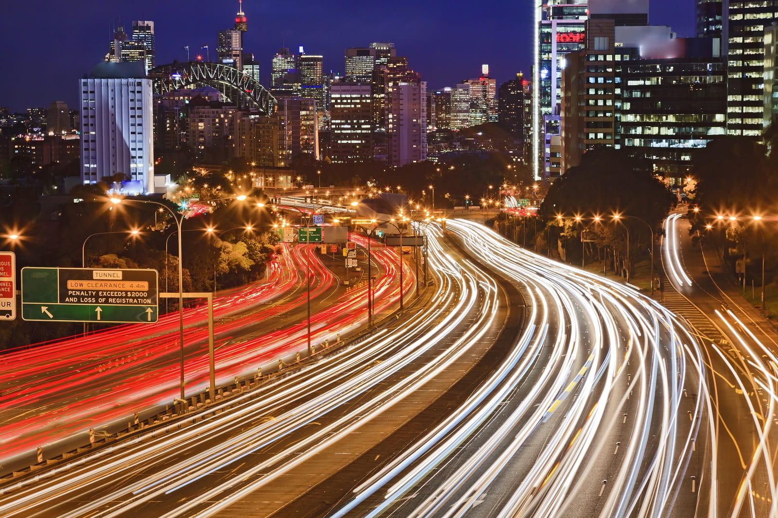 Australia NSW Sydney city Cahill expressway at sunset with long blurred traffic lights multi-lane motor road towards CBD, harbour bridge and illuminated landmarks